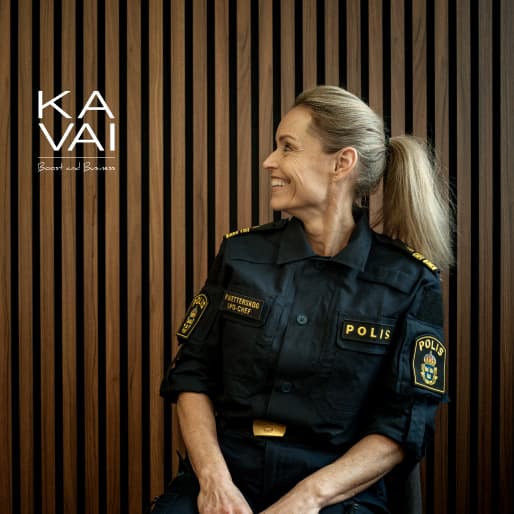 Polis iklädd i uniform sitter på en stol och ler.