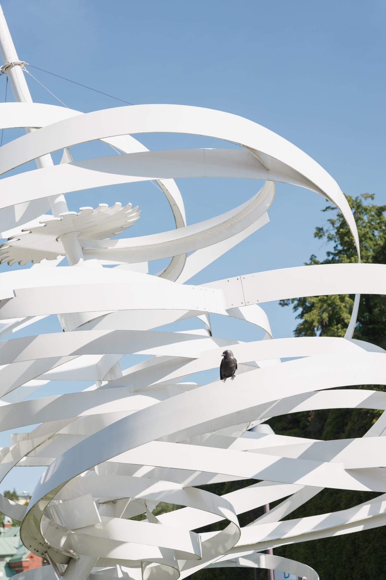 Vit abstrakt skulptur mot en blå himmel..